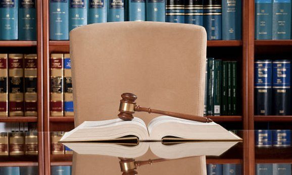 A gavel and an open book in front of law books
